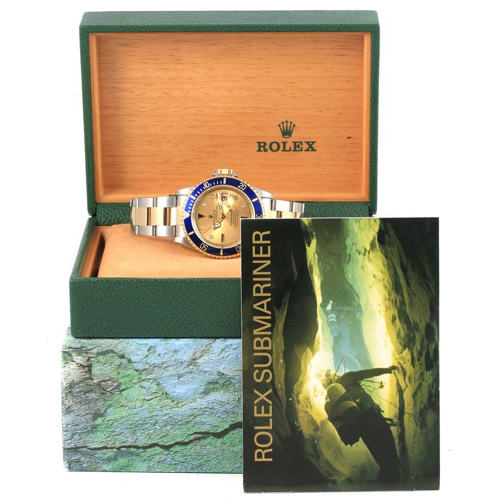 The image shows a Rolex Submariner 16613 Men's Steel and Gold (two tone) Champagne Dial 16613 Men's Steel and Gold (two tone) Champagne Dial watch in its green box with a booklet in front.