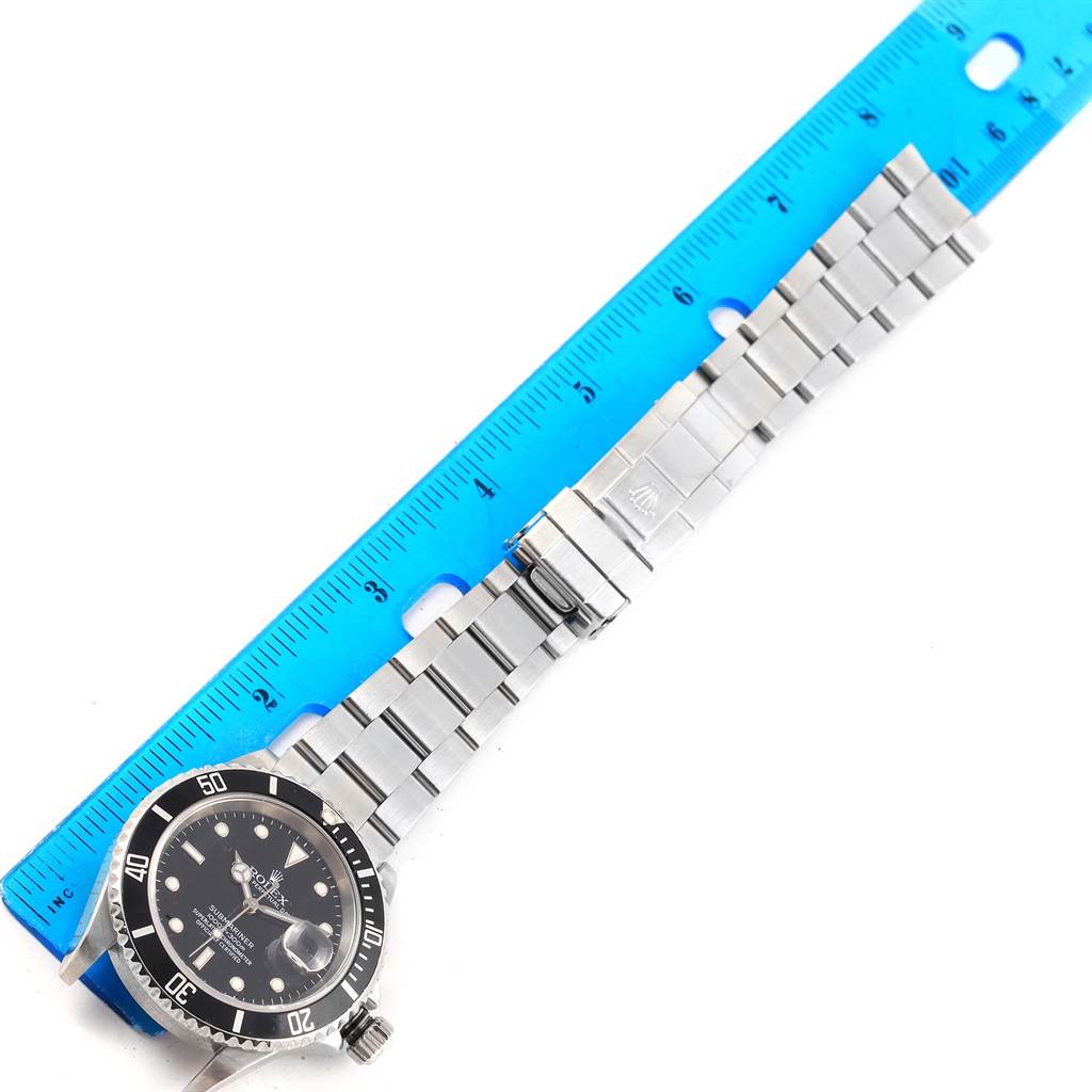 The image shows a Rolex Submariner 16610 Men's Stainless Steel Black Dial 16610 Men's Stainless Steel Black Dial watch from a top-down angle with the full bracelet laid out next to a ruler.