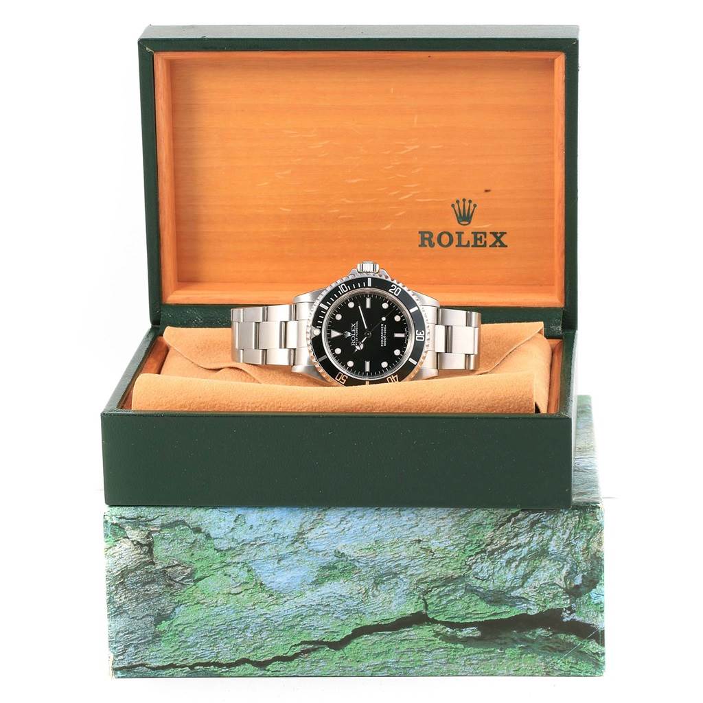 The image shows a Rolex Submariner 14060 Men's Stainless Steel Black Dial 14060 Men's Stainless Steel Black Dial watch front view, inside an open wooden Rolex box with a green exterior and a cushion.