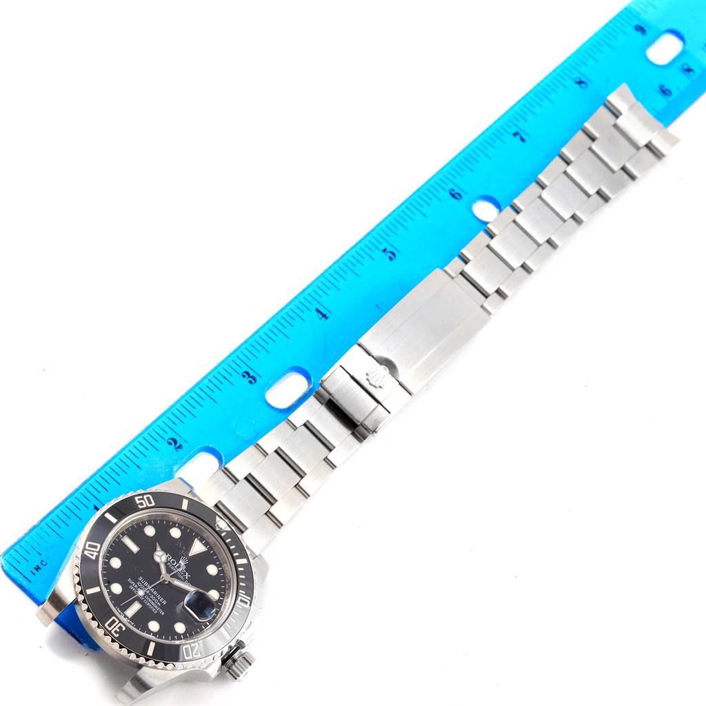 The image shows a top-down view of a Rolex Submariner 116610 Men's Stainless Steel Black Dial 116610 Men's Stainless Steel Black Dial watch with a blue ruler for scale, highlighting the face, bezel, and bracelet.