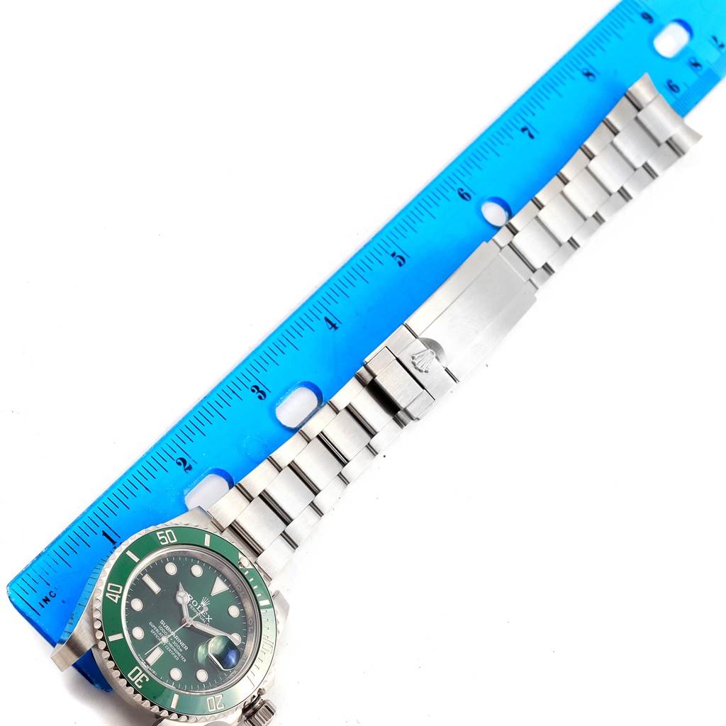 The image shows a top-down view of a Rolex Submariner 116610LV Men
s Stainless Steel Green Dial 116610LV Men
s Stainless Steel Green Dial watch with a green bezel and a stainless steel bracelet fully extended next to a ruler.