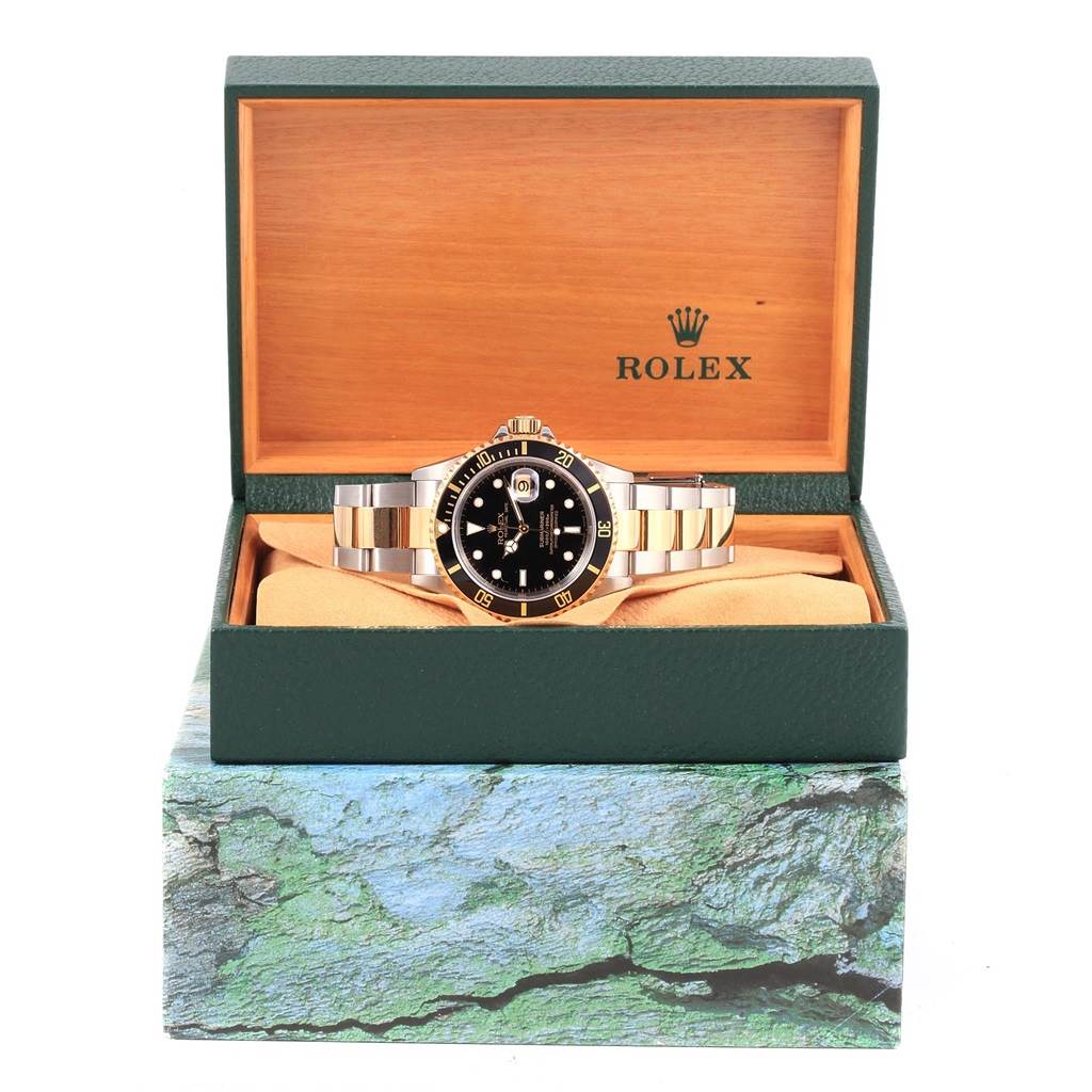 The image shows a Rolex Submariner 16613 Men's Steel and Gold (two tone) Black Dial 16613 Men's Steel and Gold (two tone) Black Dial watch from a front angle, inside its green and gold presentation box.