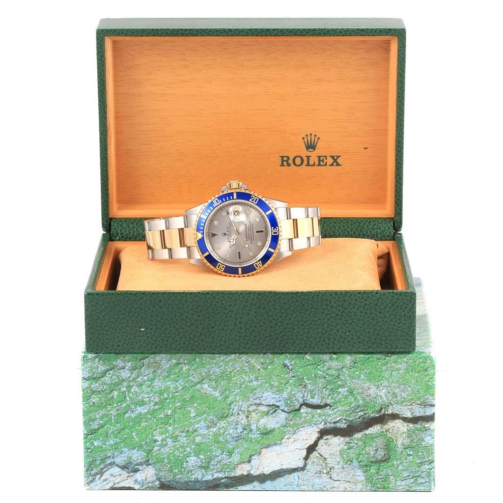 The image shows the Rolex Submariner 16613 Men's Steel and Gold (two tone) Grey Dial 16613 Men's Steel and Gold (two tone) Grey Dial watch front-facing, placed inside its green case with the lid open.