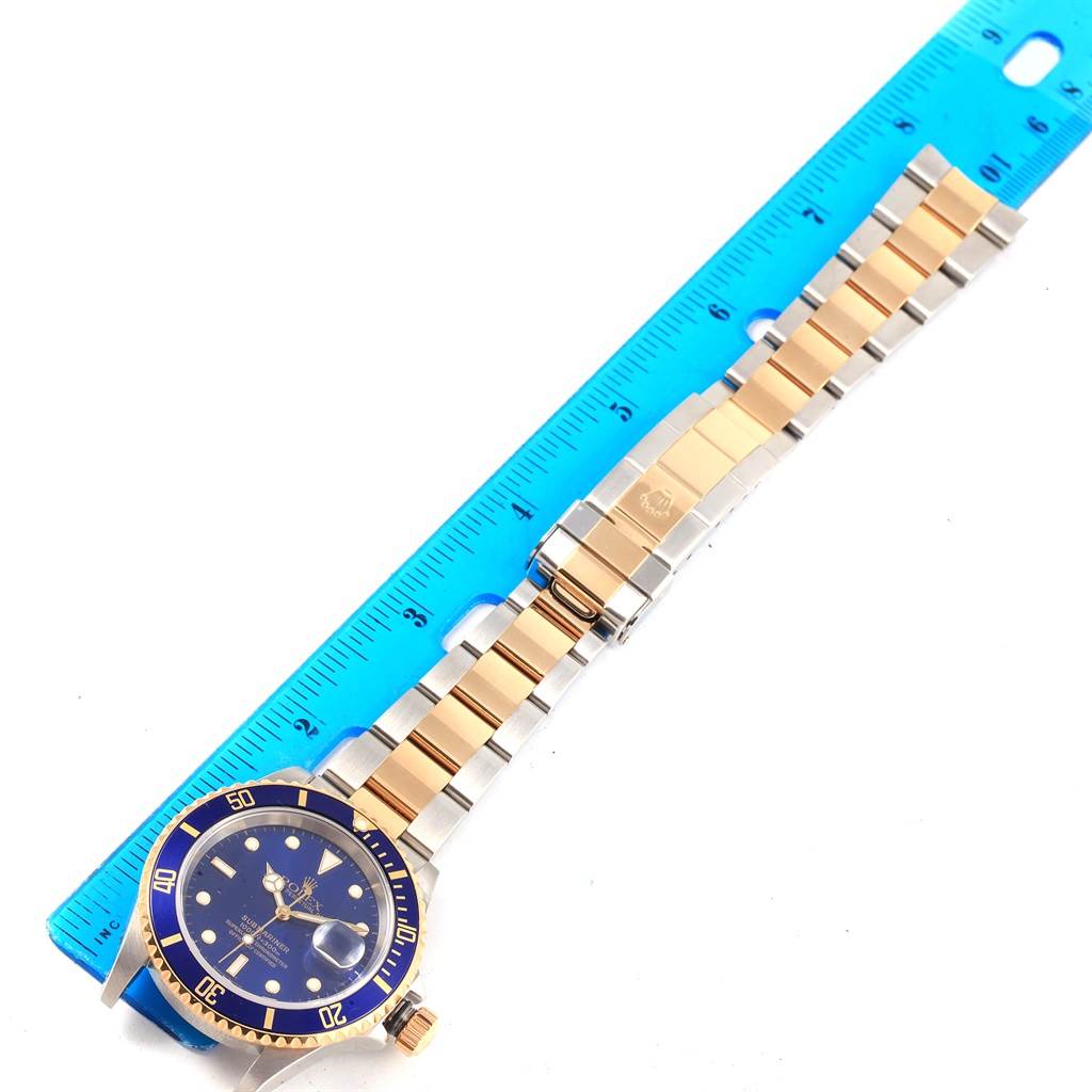 This image shows a Rolex Submariner 16613 Men's Steel and Gold (two tone) Blue Dial 16613 Men's Steel and Gold (two tone) Blue Dial watch from a top view, highlighting the watch face, bezel, and bracelet placed beside a ruler.