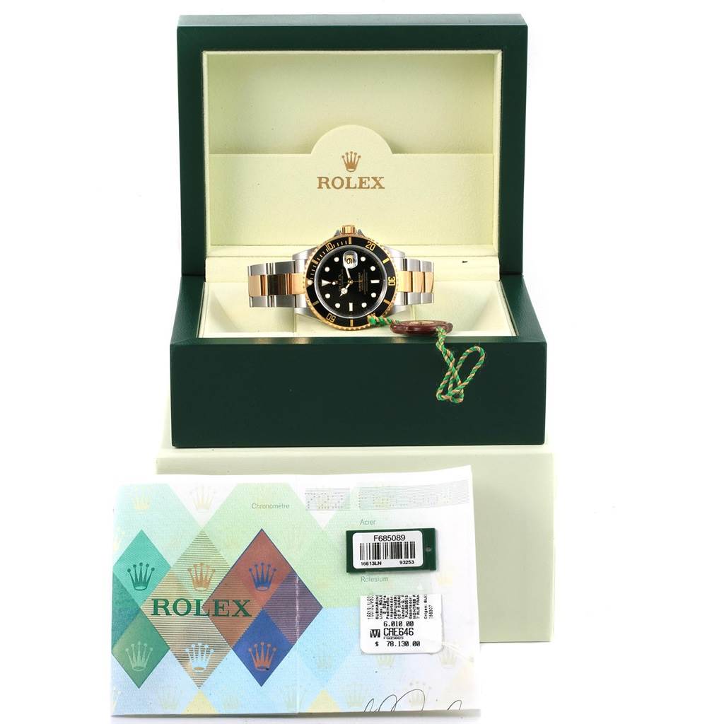 The Rolex Submariner 16613 Men's Steel and Gold (two tone) Black Dial 16613 Men's Steel and Gold (two tone) Black Dial watch is displayed front-facing in an open Rolex box, alongside its documentation and tags underneath.