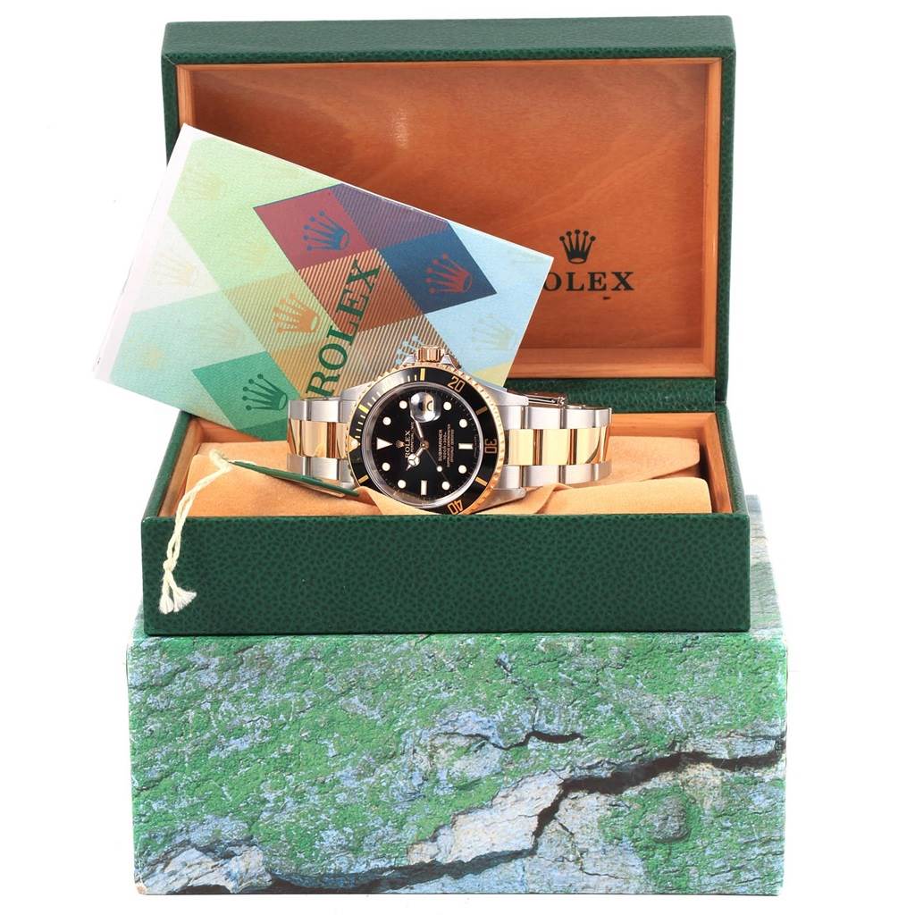 The Rolex Submariner 16613 Men's Steel and Gold (two tone) Black Dial 16613 Men's Steel and Gold (two tone) Black Dial watch is displayed front-facing in its open green box, accompanied by documentation.