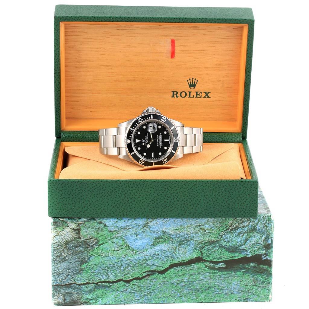 The image shows a Rolex Submariner 16610 Men's Stainless Steel Black Dial 16610 Men's Stainless Steel Black Dial watch displayed front-on in an open green and wooden Rolex box.