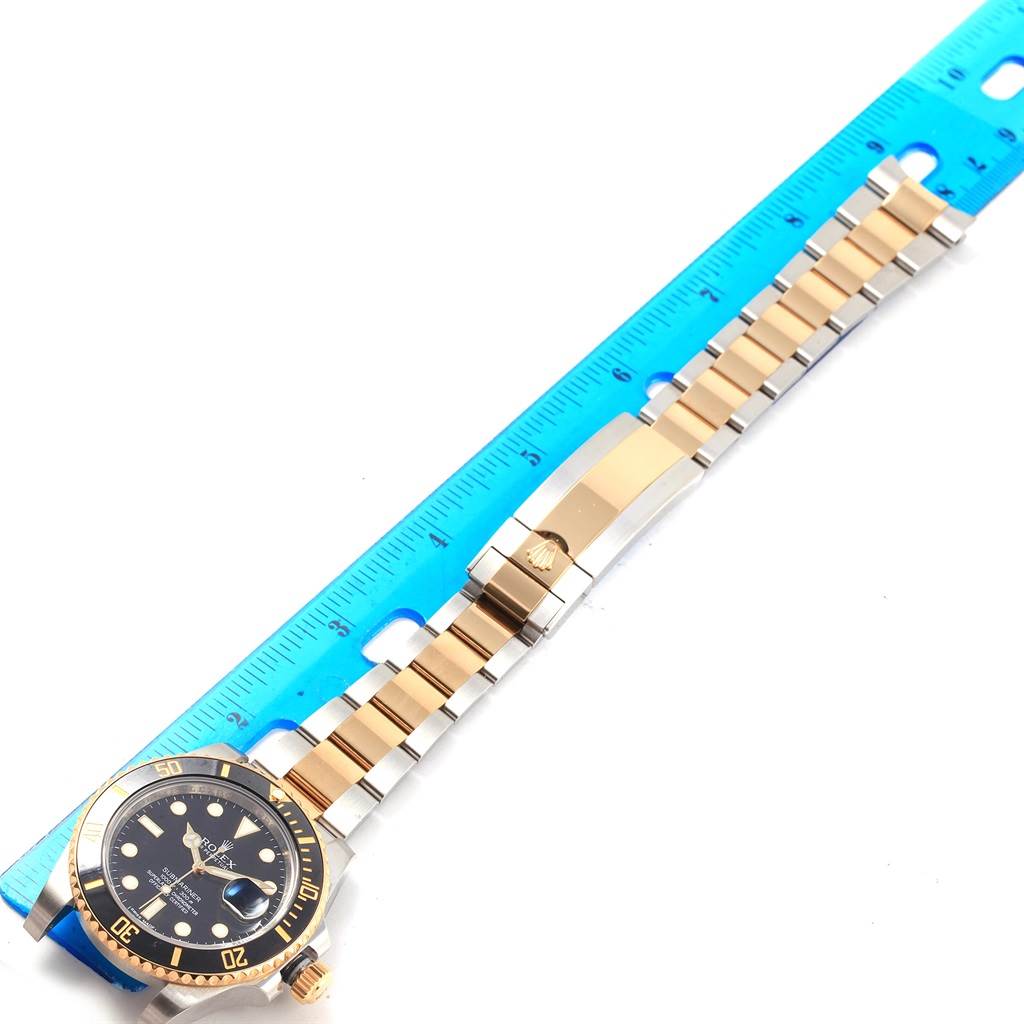 The image shows a Rolex Submariner 116613 Men's Steel and Gold (two tone) Black Dial 116613 Men's Steel and Gold (two tone) Black Dial watch with its dial, bezel, and bracelet laid flat next to a measuring ruler.