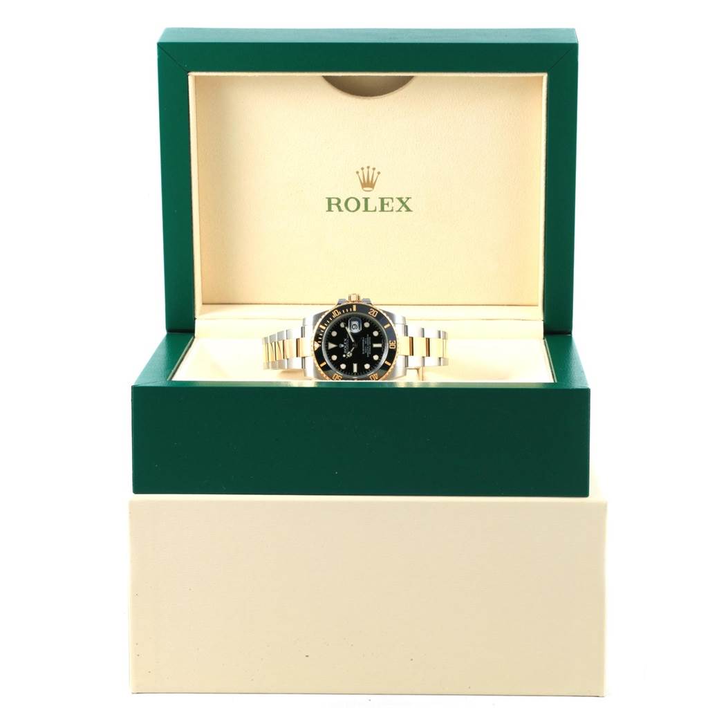 The Rolex Submariner 116613 Men's Steel and Gold (two tone) Black Dial 116613 Men's Steel and Gold (two tone) Black Dial watch is shown front-facing inside an open green and beige Rolex box.