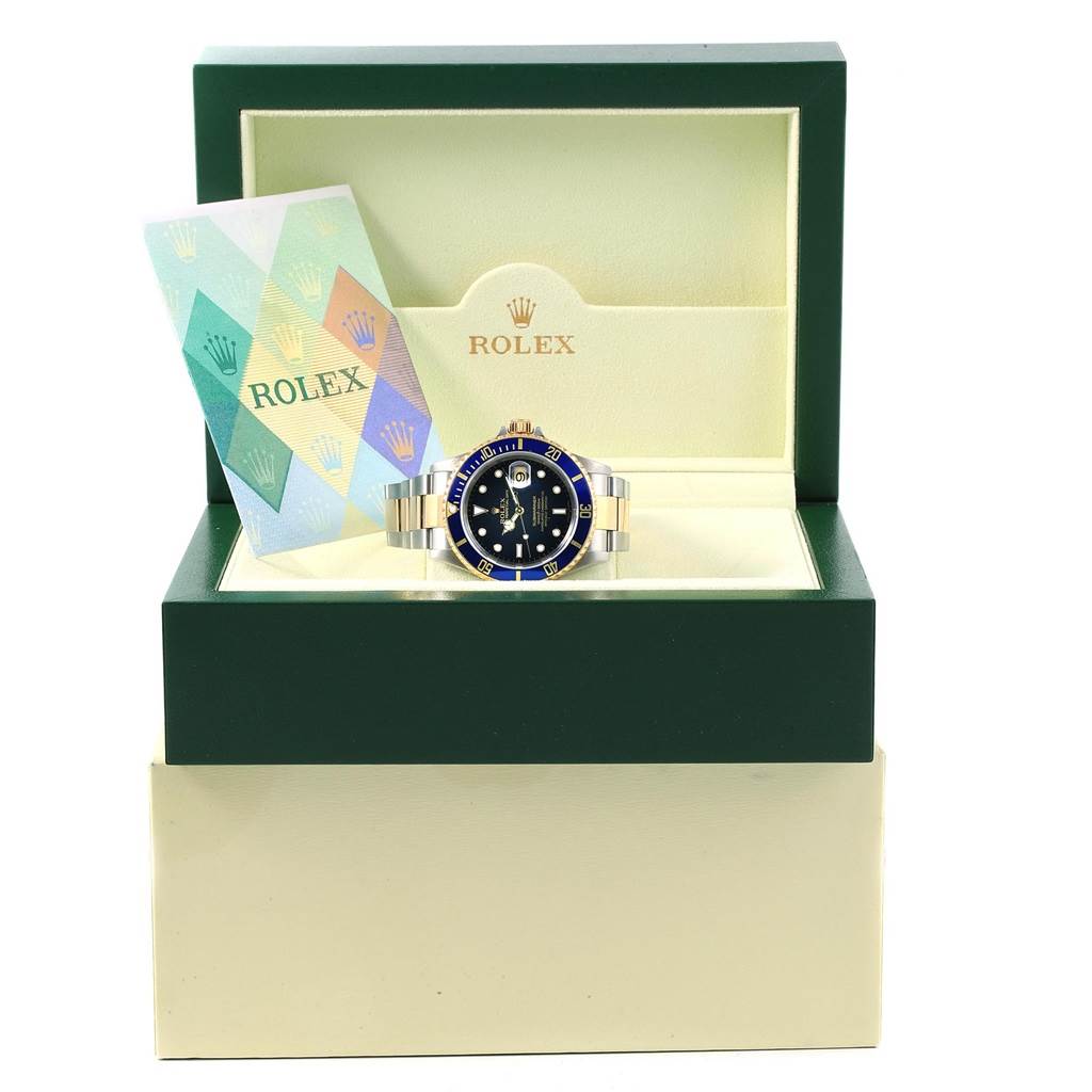 The Rolex Submariner 16613 Men's Steel and Gold (two tone) Blue Dial 16613 Men's Steel and Gold (two tone) Blue Dial watch is displayed front-facing in its open box, alongside the warranty card.