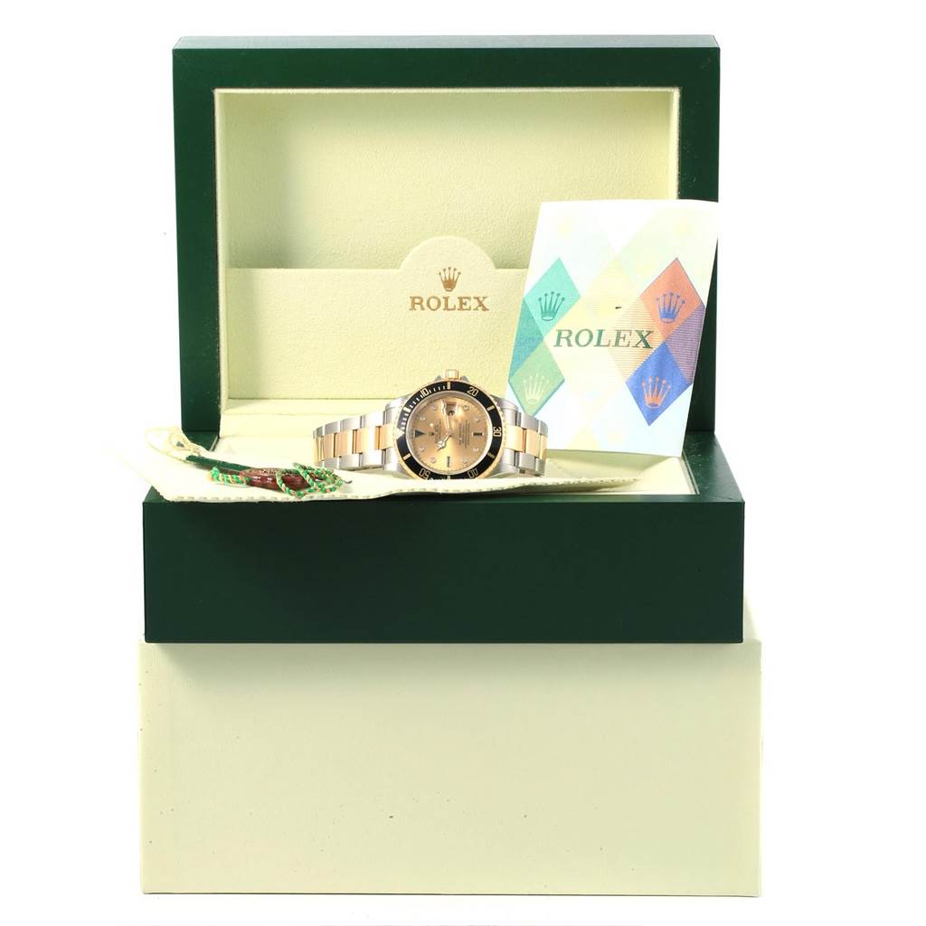 The image shows a Rolex Submariner 16613 Men's Steel and Gold (two tone) Champagne Dial 16613 Men's Steel and Gold (two tone) Champagne Dial watch in its open box, accompanied by a booklet and tag, photographed from the front.