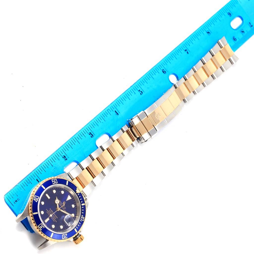 The image shows a Rolex Submariner 16613 Men's Steel and Gold (two tone) Blue Dial 16613 Men's Steel and Gold (two tone) Blue Dial watch, including the face, bezel, and entire bracelet, measured against a blue ruler.