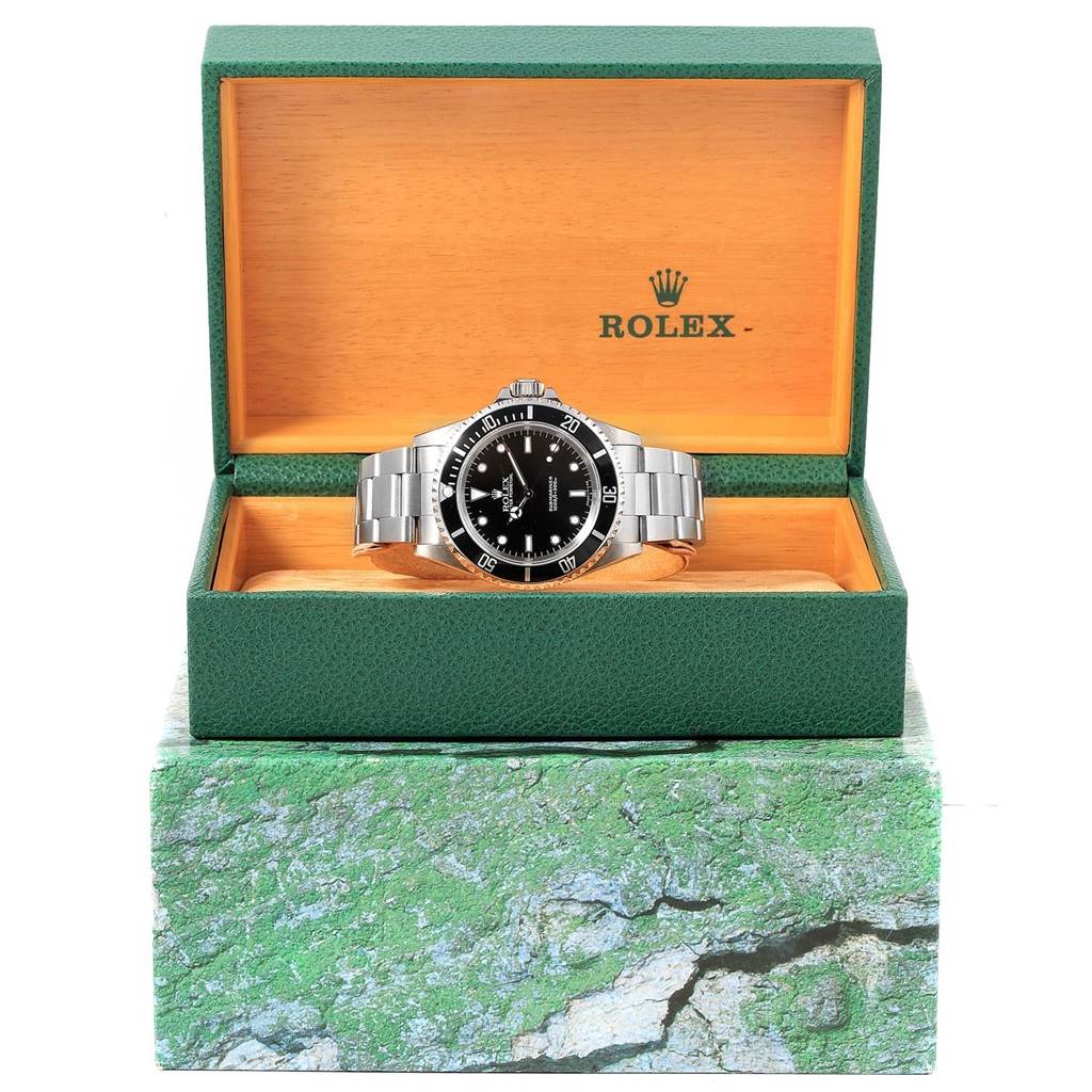 The Rolex Submariner 14060 Men's Stainless Steel Black Dial 14060 Men's Stainless Steel Black Dial watch is displayed head-on inside an open green and orange box with the brand logo visible.