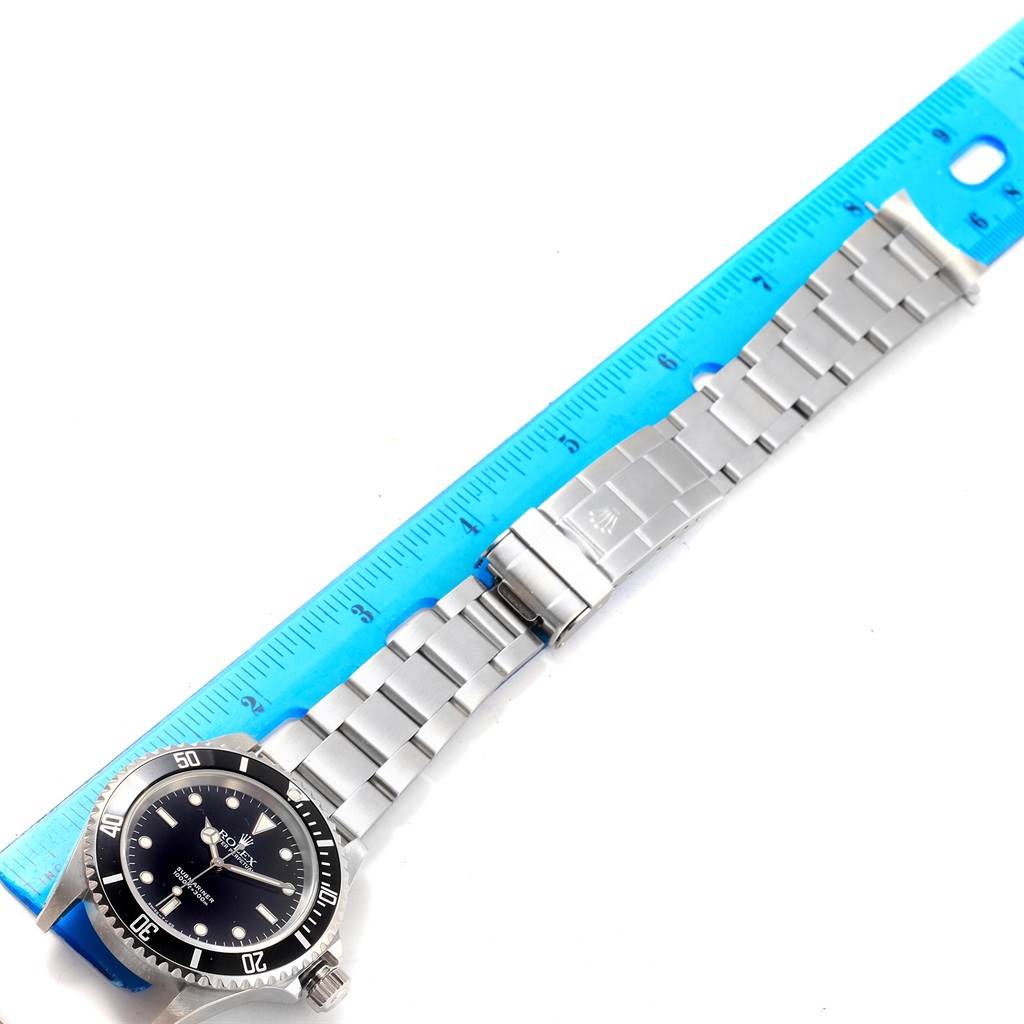 The image shows a Rolex Submariner 14060 Men's Stainless Steel Black Dial 14060 Men's Stainless Steel Black Dial watch laid flat, with its full bracelet and clasp displayed alongside a blue ruler.