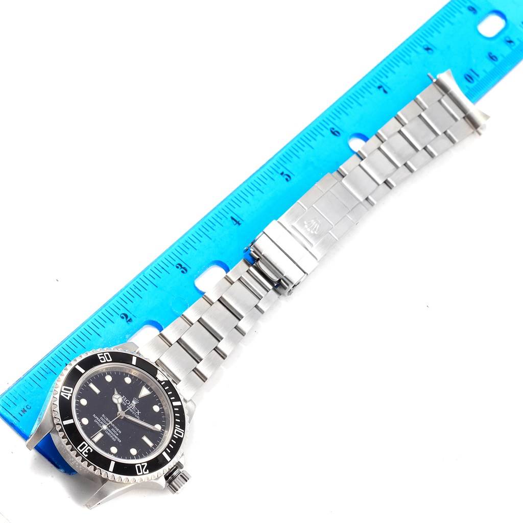 The Rolex Submariner 14060 Men's Stainless Steel Black Dial 14060 Men's Stainless Steel Black Dial watch is shown from a top-down angle with its bracelet fully extended next to a ruler.