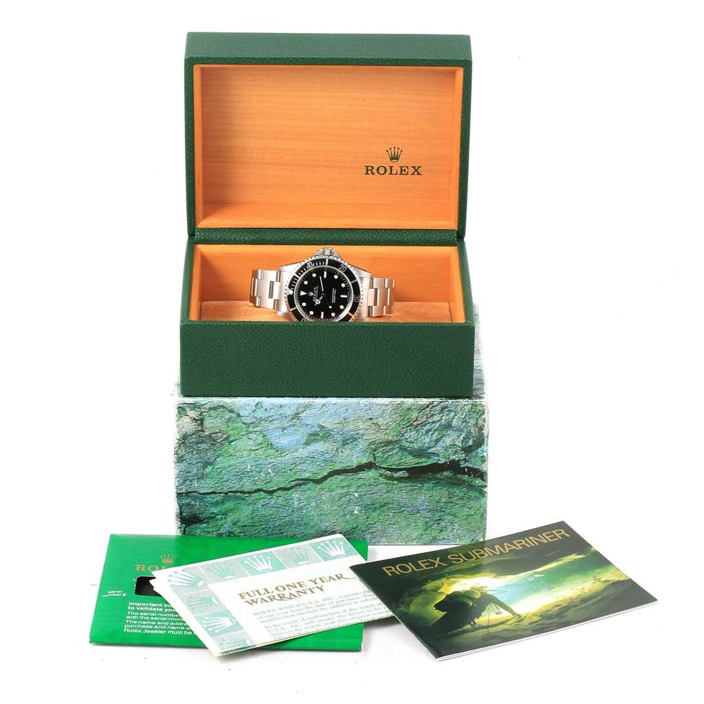 The image shows a Rolex Submariner 14060 Men's Stainless Steel Black Dial 14060 Men's Stainless Steel Black Dial watch in an open green box, along with warranty papers and a user manual.