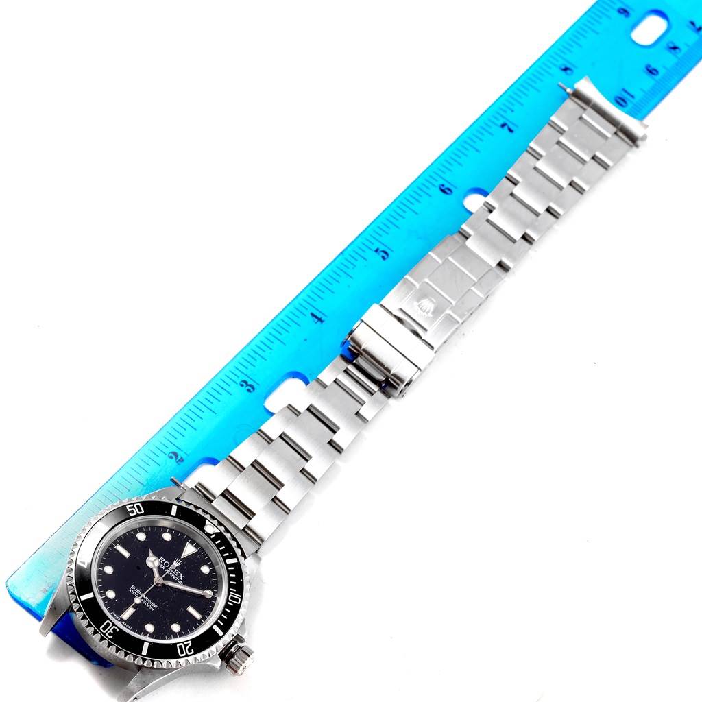 This image shows a Rolex Submariner 14060 Men's Stainless Steel Black Dial 14060 Men's Stainless Steel Black Dial watch laid flat beside a blue ruler, displaying the band and face from a top-down angle.