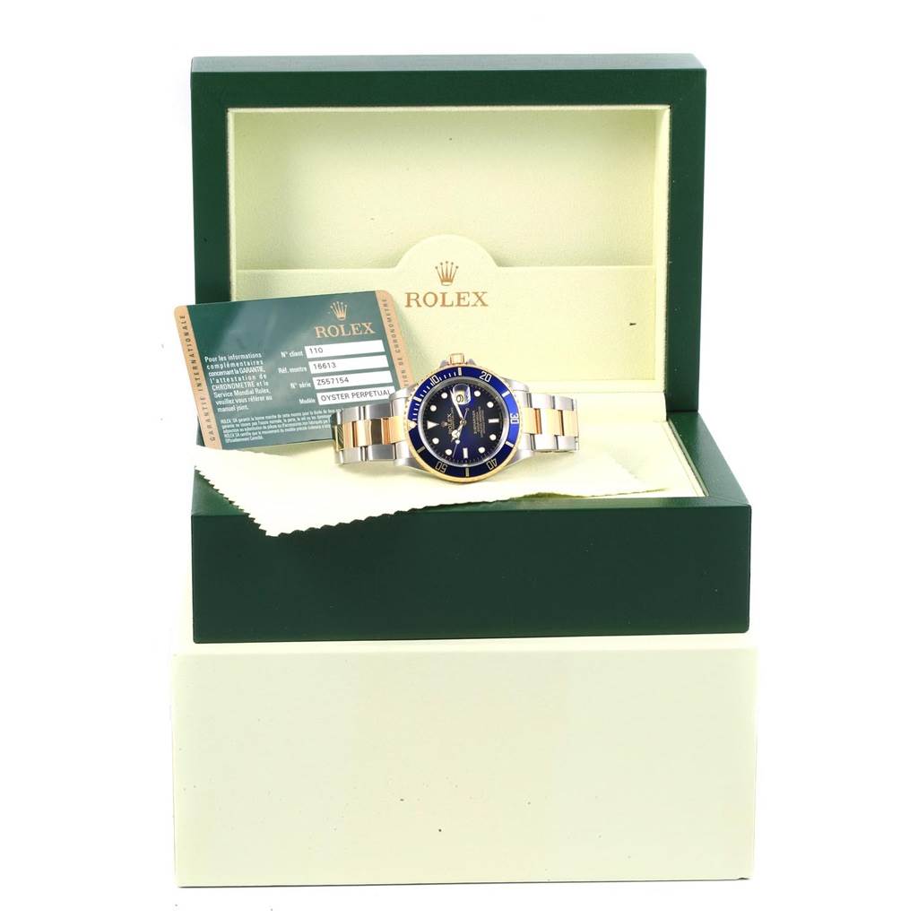 The image shows a front view of a Rolex Submariner 16613 Men's Steel and Gold (two tone) Blue Dial 16613 Men's Steel and Gold (two tone) Blue Dial watch placed in its box along with the warranty card.