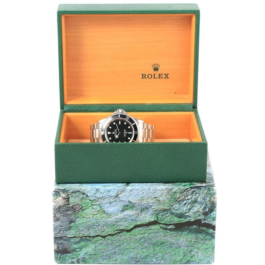 The Rolex Submariner 14060 Men's Stainless Steel Black Dial 14060 Men's Stainless Steel Black Dial watch is displayed front-facing inside an open green and wood box.