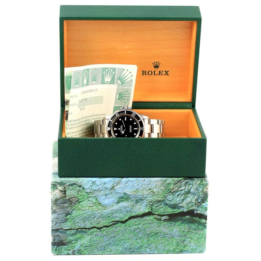 The image shows a Rolex Submariner 14060 Men's Stainless Steel Black Dial 14060 Men's Stainless Steel Black Dial watch placed inside its open green box with official papers.