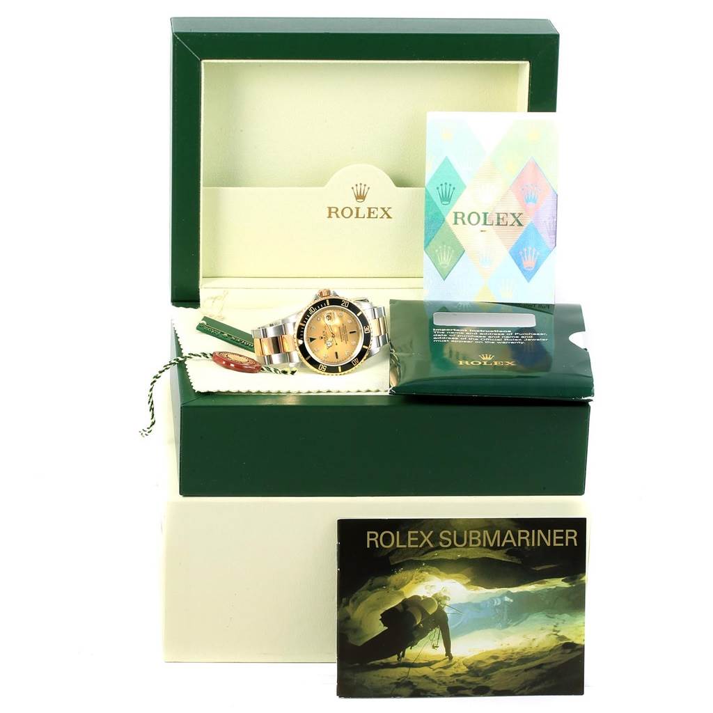 The image shows a Rolex Submariner 16613 Men's Steel and Gold (two tone) Champagne Dial 16613 Men's Steel and Gold (two tone) Champagne Dial watch in its box, accompanied by booklets and warranty cards.