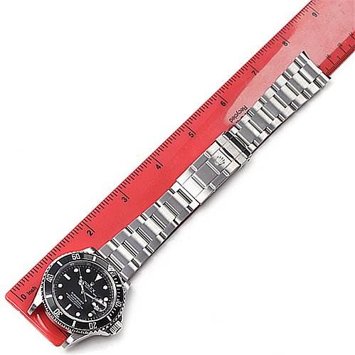 The image shows a Rolex Submariner 16610 Men's Stainless Steel Black Dial 16610 Men's Stainless Steel Black Dial watch laid out flat alongside a red ruler, displaying the full bracelet and watch face from an overhead angle.