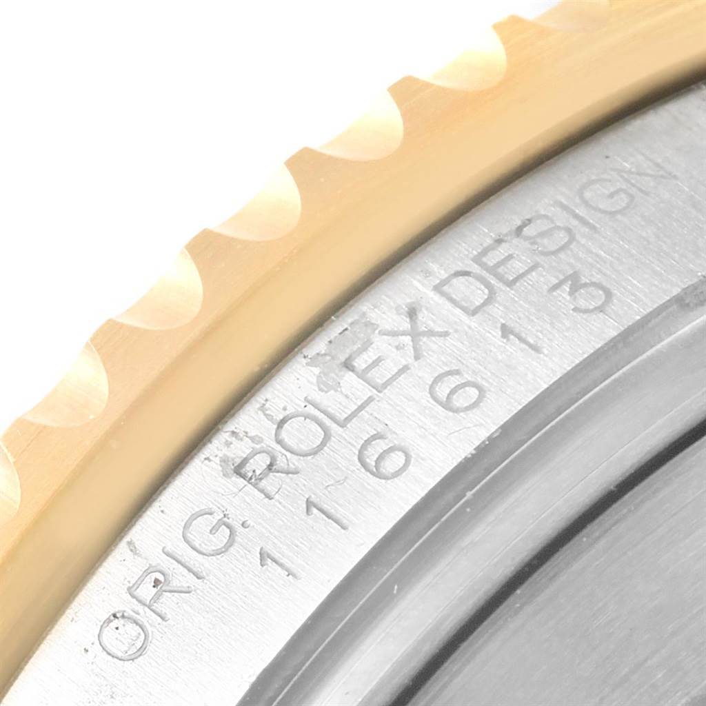 The image shows a close-up angle of the bezel and part of the case back of a Rolex Submariner 116613 Men's Steel and Gold (two tone) Black Dial 116613 Men's Steel and Gold (two tone) Black Dial watch, featuring engraved text.