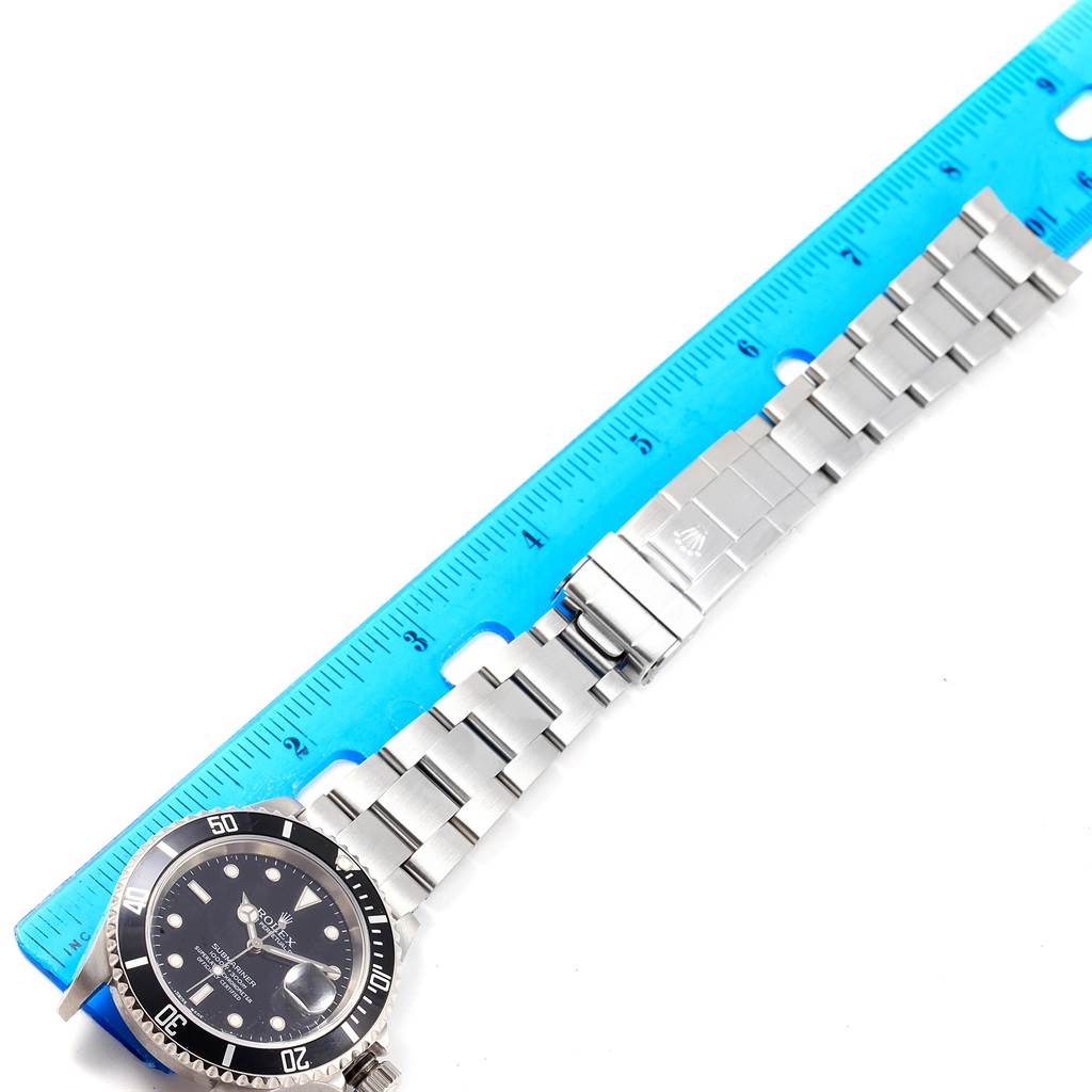 The image shows a Rolex Submariner 16610 Men's Stainless Steel Black Dial 16610 Men's Stainless Steel Black Dial watch laid flat, with the dial and stainless steel bracelet measured alongside a blue ruler.