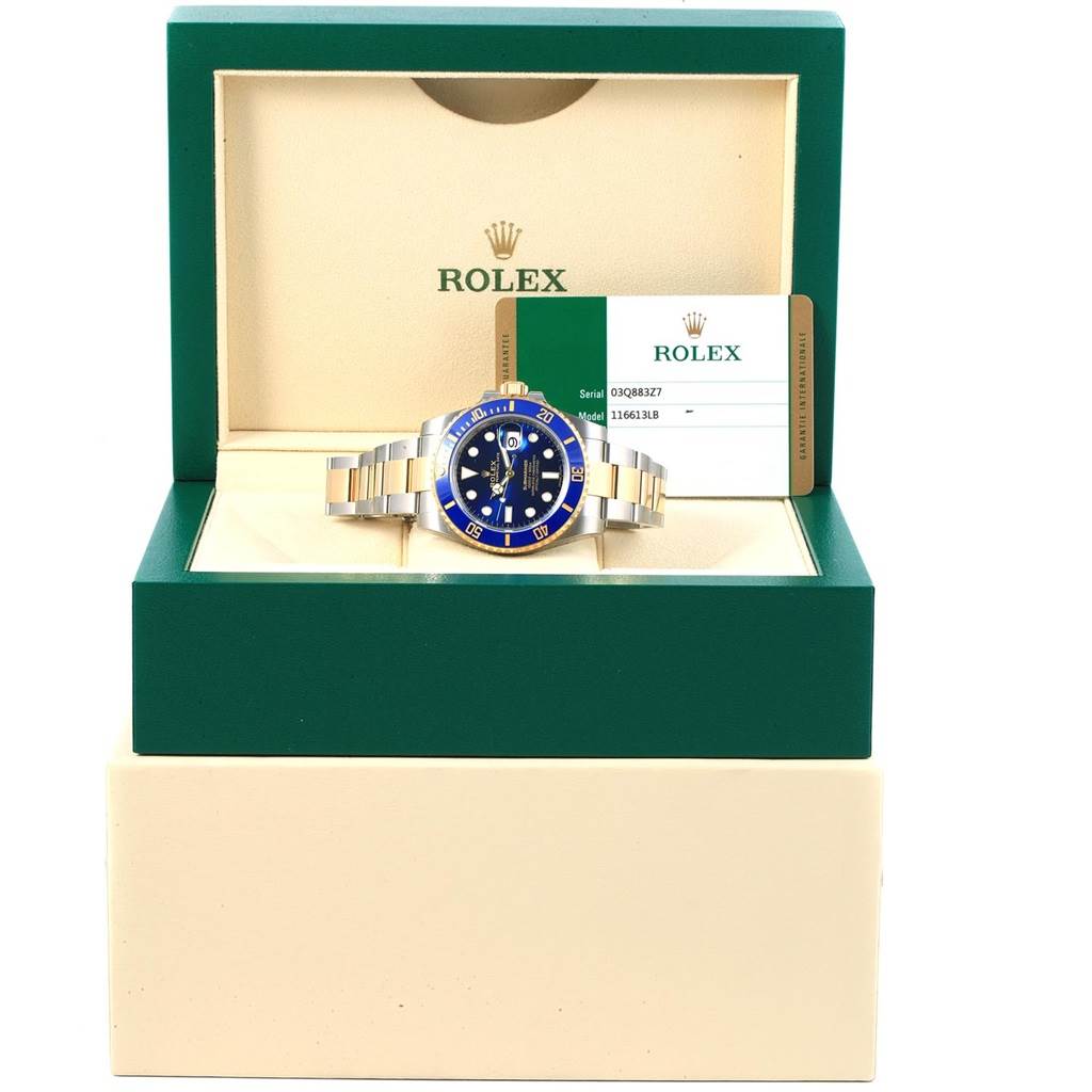 This image shows a Rolex Submariner 116613 Men's Steel and Gold (two tone) Blue Dial 116613 Men's Steel and Gold (two tone) Blue Dial watch at a front angle in its open box, along with a warranty card.