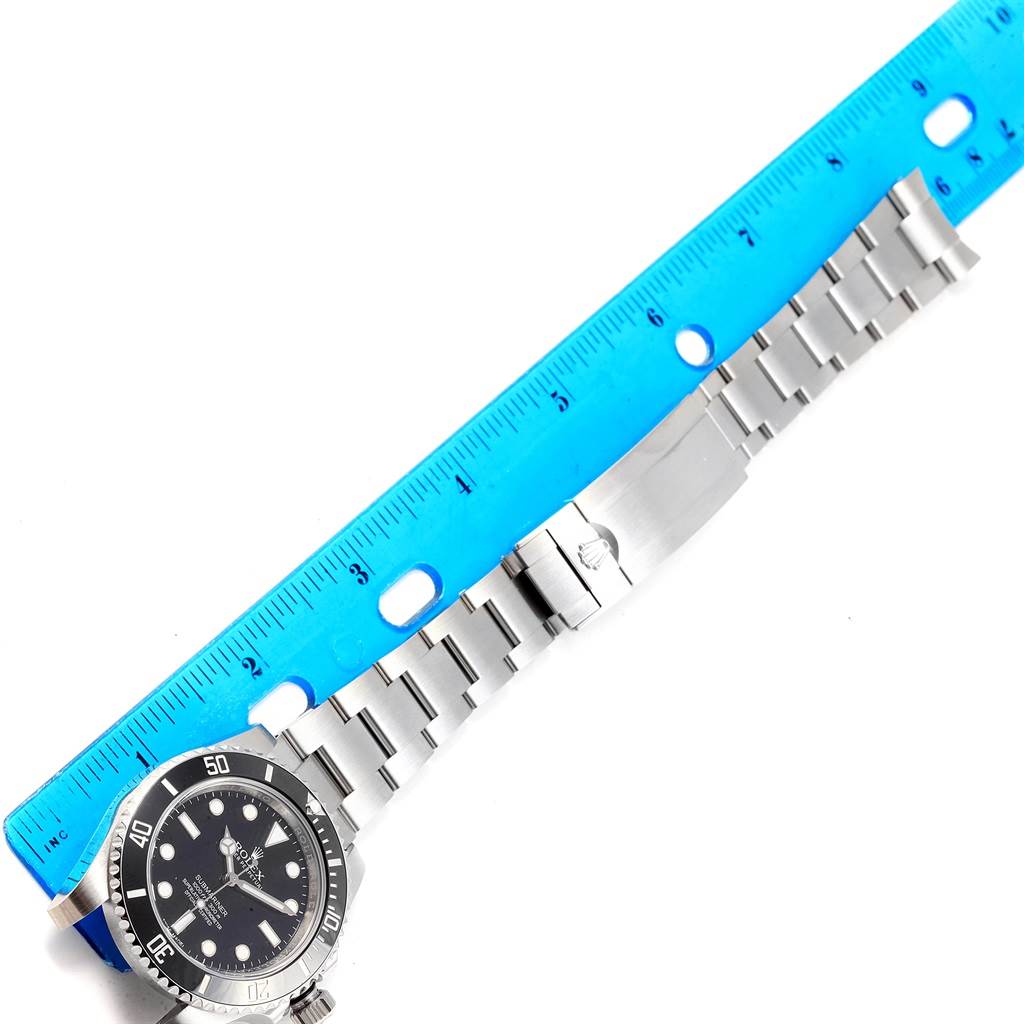 This image features a Rolex Submariner 114060 Men's Stainless Steel Black Dial 114060 Men's Stainless Steel Black Dial watch showing its face and stainless steel bracelet, accompanied by a ruler for scale.