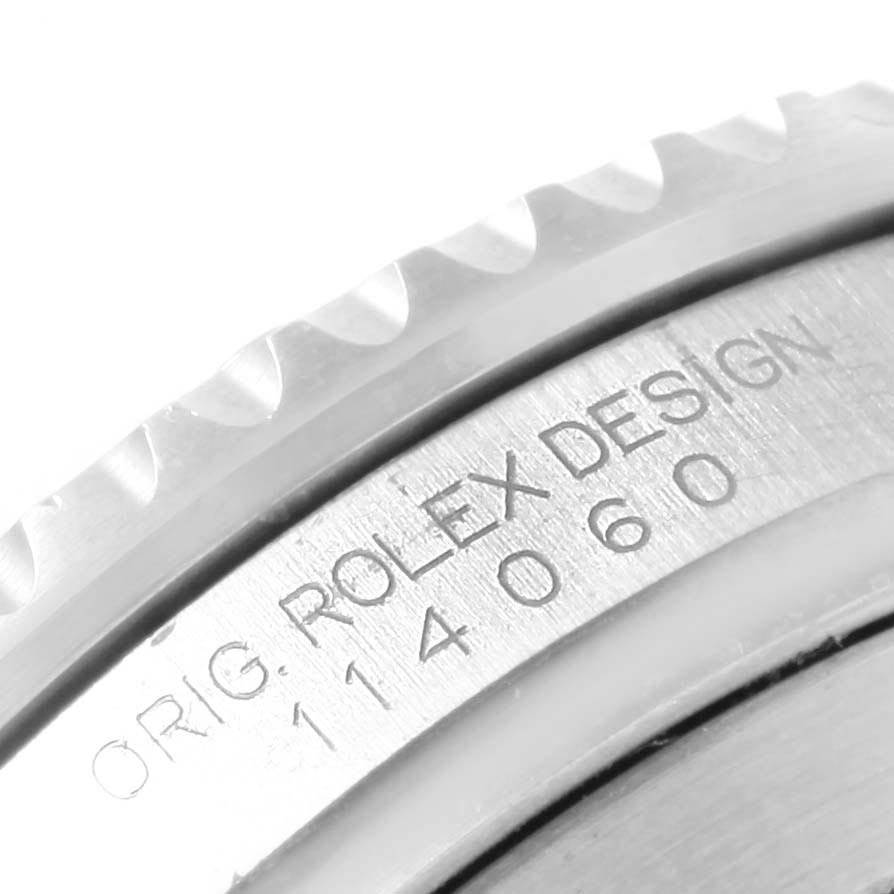 The image shows a close-up of the engraved case back and the fluted bezel edge of a Rolex Submariner 114060 Men's Stainless Steel Black Dial 114060 Men's Stainless Steel Black Dial.