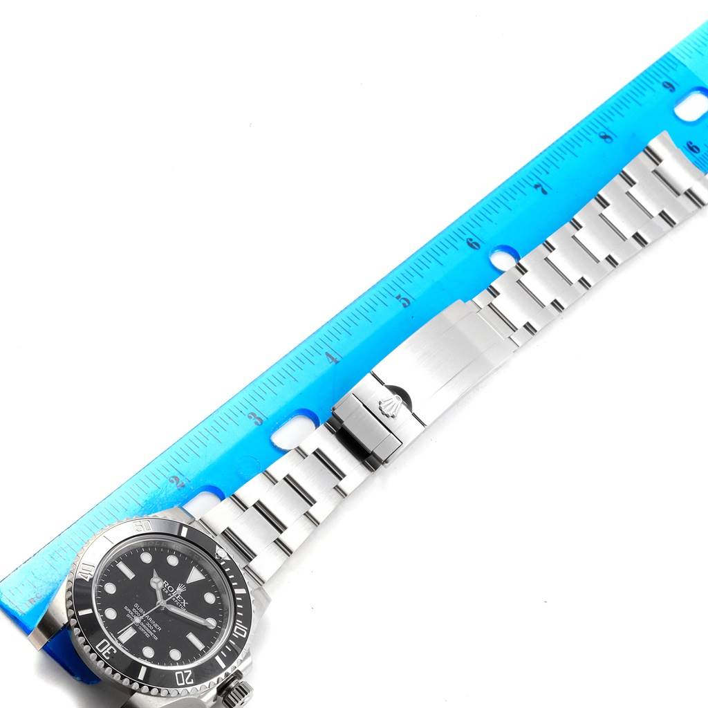 The image shows a Rolex Submariner 114060 Men's Stainless Steel Black Dial 114060 Men's Stainless Steel Black Dial watch with a metal bracelet laid flat next to a blue ruler.