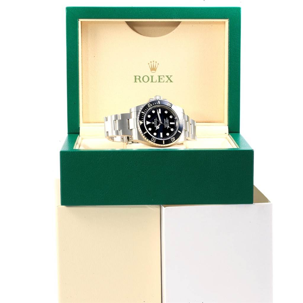 The Rolex Submariner 114060 Men
s Stainless Steel Black Dial 114060 Men
s Stainless Steel Black Dial watch is shown from a front angle inside its green and beige box, displaying the face and bracelet.