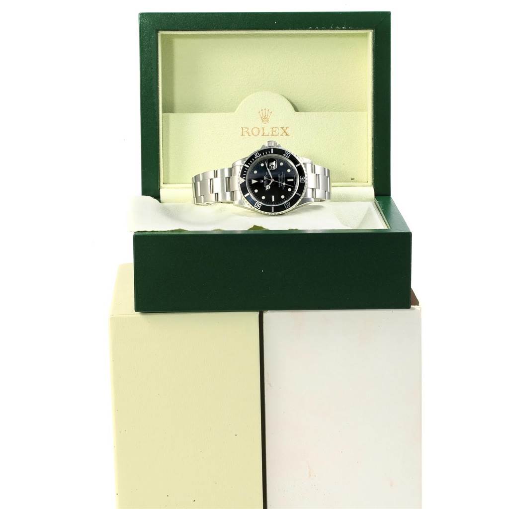 The Rolex Submariner 16610 Men
s Stainless Steel Black Dial 16610 Men
s Stainless Steel Black Dial watch is displayed inside its green and cream box at a front angle.