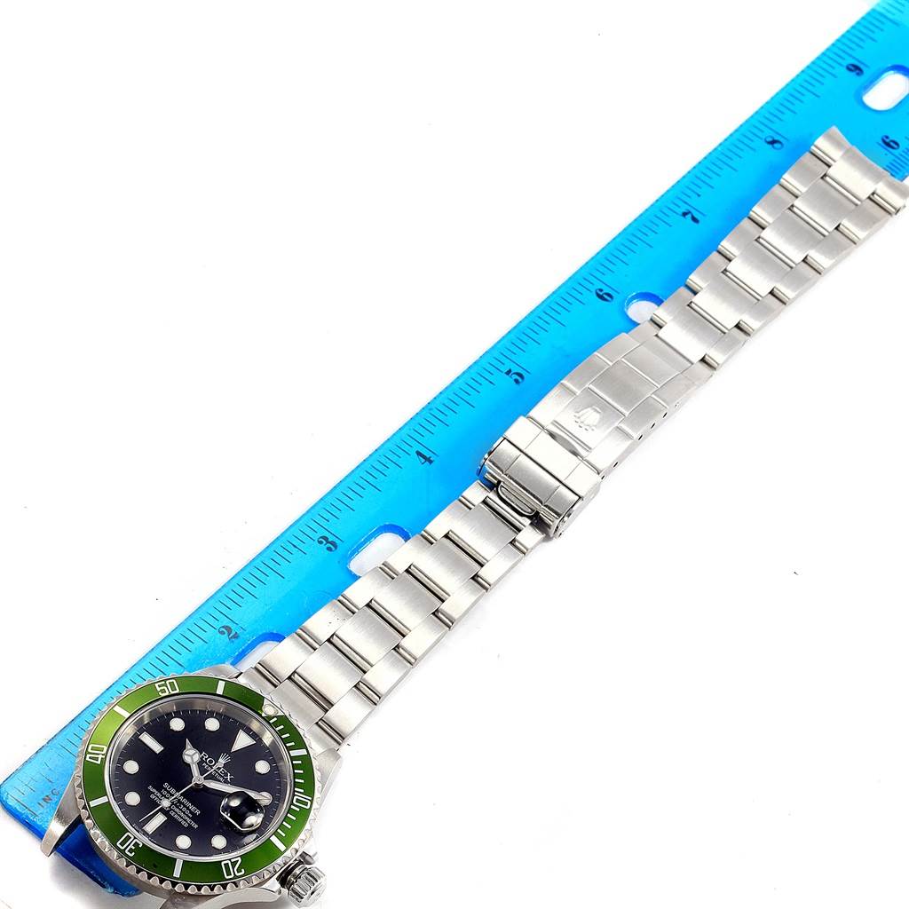 The image shows a top-down view of a Rolex Submariner 16610LV Men
s Stainless Steel Black Dial 16610LV Men
s Stainless Steel Black Dial watch, displaying the full length, bracelet, and clasp next to a blue ruler.