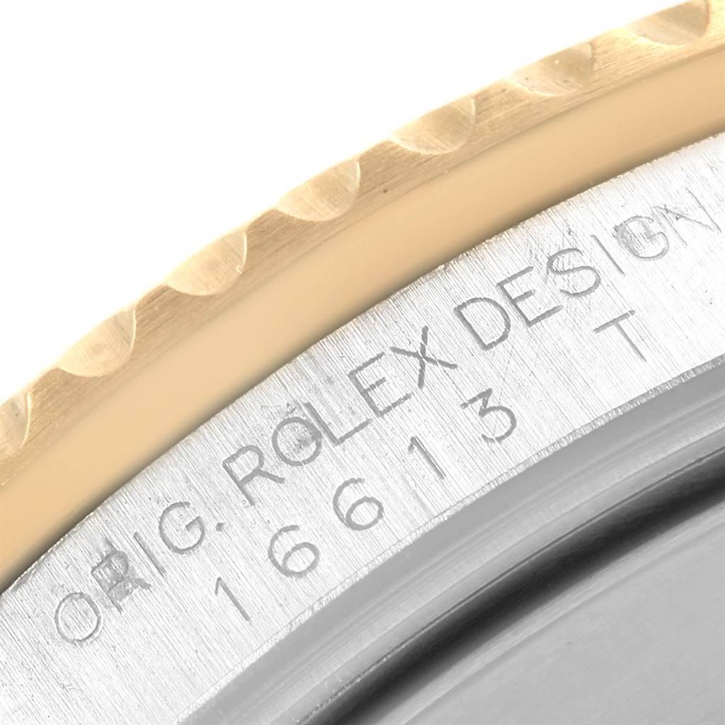 The image shows a close-up of the Rolex Submariner 16613 Men
s Steel and Gold (two tone) Grey Dial 16613 Men
s Steel and Gold (two tone) Grey Dial model bezel and case side with engraved inscriptions.