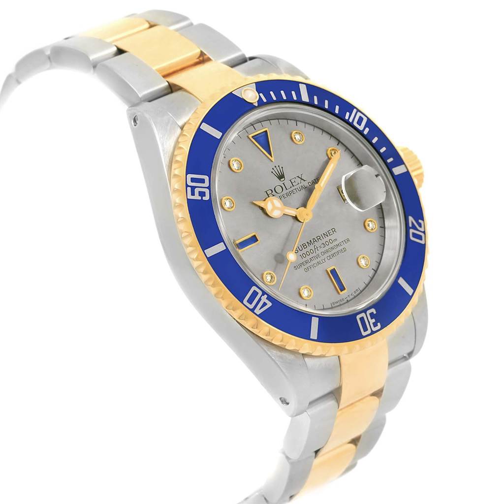 The image shows a Rolex Submariner 16613 Men
s Steel and Gold (two tone) Grey Dial 16613 Men
s Steel and Gold (two tone) Grey Dial watch at a three-quarter angle, highlighting its two-tone bracelet, blue bezel, and grey dial.