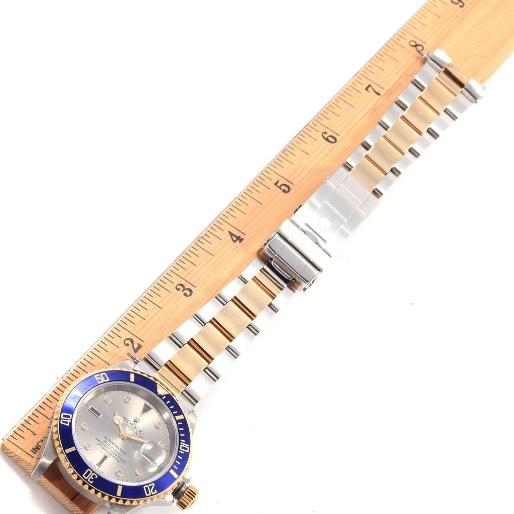 This image shows a Rolex Submariner 16613 Men
s Steel and Gold (two tone) Grey Dial 16613 Men
s Steel and Gold (two tone) Grey Dial watch laid flat with a ruler beside it, displaying the face, bezel, and metal bracelet.