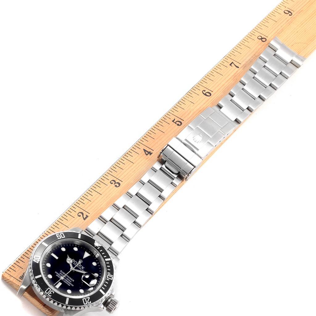 This image shows a Rolex Submariner 16610 Men
s Stainless Steel Black Dial 16610 Men
s Stainless Steel Black Dial watch laid flat with a ruler for scale, displaying the face, bezel, and bracelet.