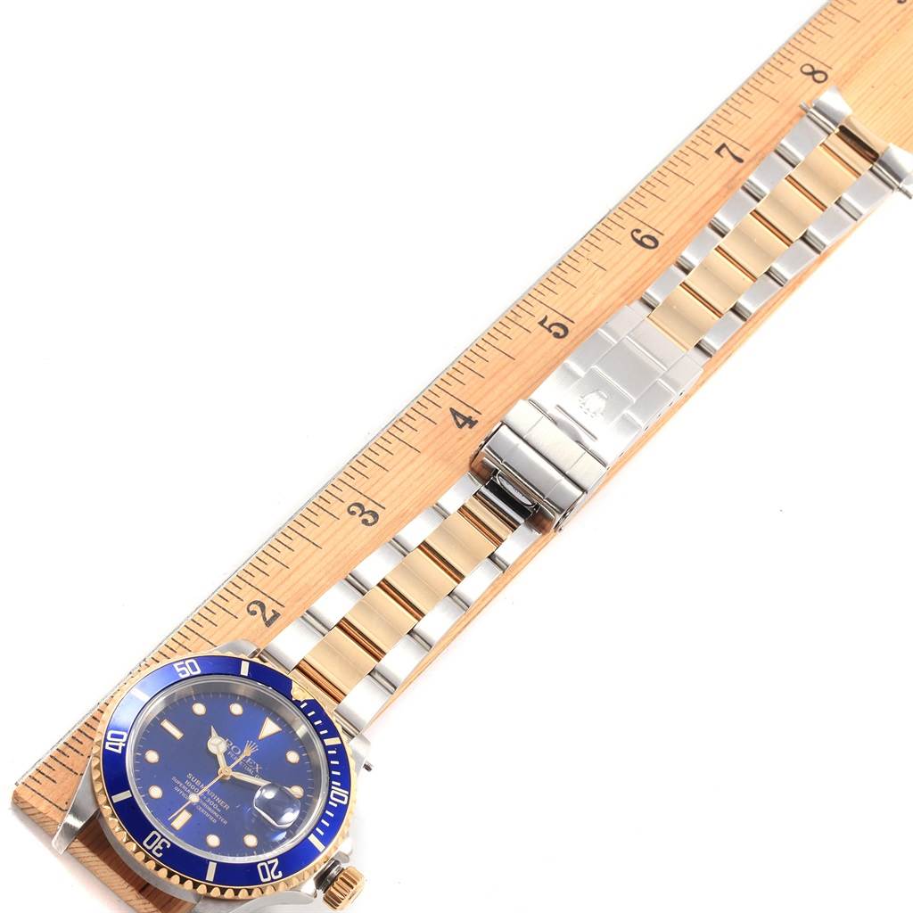 This image shows a top-down view of a Rolex Submariner 16613 Men's Steel and Gold (two tone) Blue Dial 16613 Men's Steel and Gold (two tone) Blue Dial watch, including its blue dial, bezel, and metal bracelet beside a ruler.