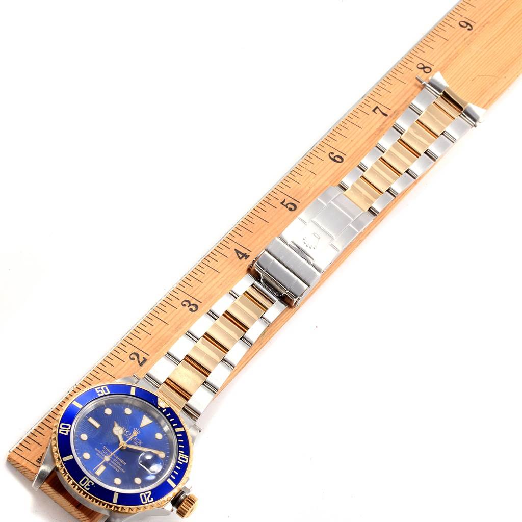 The Rolex Submariner 16803 Men's Steel and Gold (two tone) Blue Dial 16803 Men's Steel and Gold (two tone) Blue Dial watch is shown flat with its bracelet extended along a ruler, displaying the face, bezel, and bracelet.