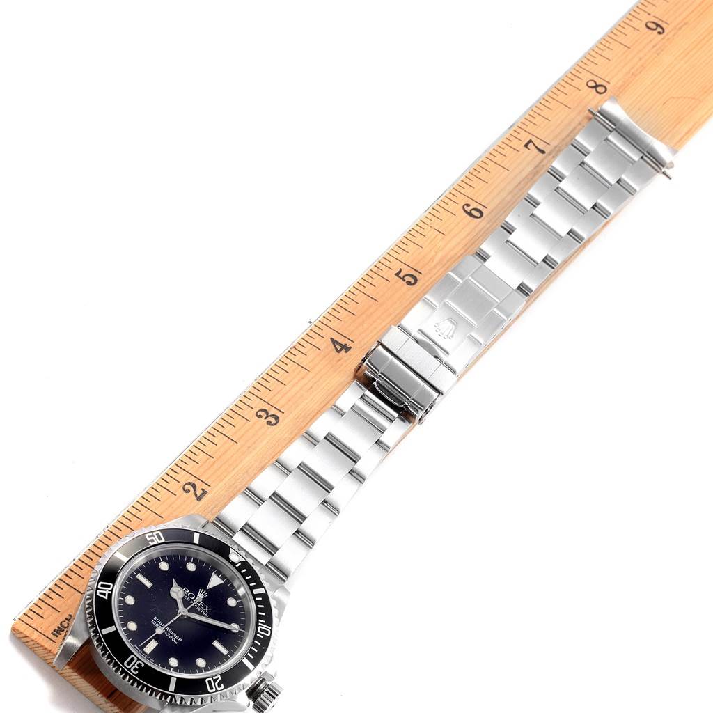 The image shows a Rolex Submariner 14060 Men
s Stainless Steel Black Dial 14060 Men
s Stainless Steel Black Dial watch laid flat next to a ruler, displaying the watch face and bracelet.