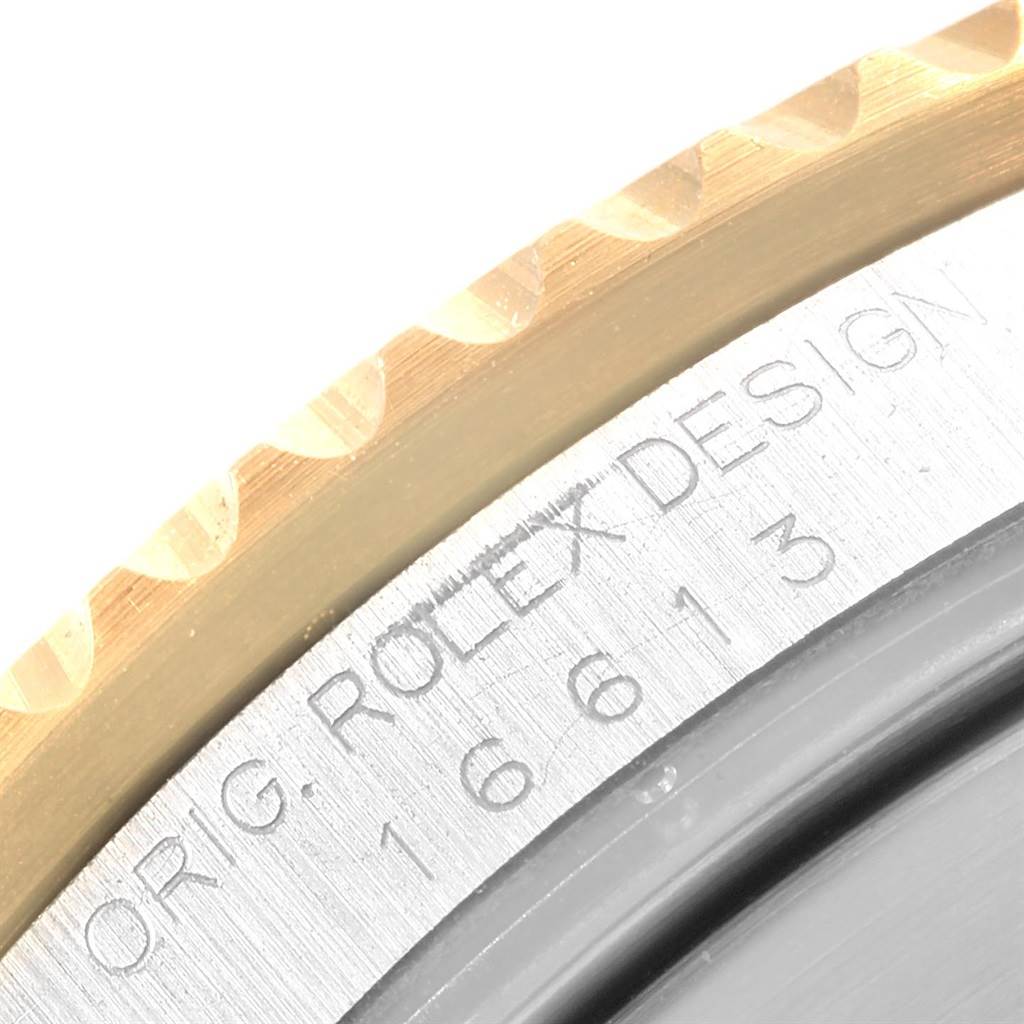 The image shows a close-up of the bezel and engraved text on a Rolex Submariner 16613 Men's Steel and Gold (two tone) Black Dial 16613 Men's Steel and Gold (two tone) Black Dial watch.