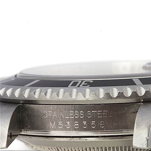 This image shows a close-up side angle of the bezel and case of a Rolex Submariner 16610 Men's Stainless Steel Black Dial 16610 Men's Stainless Steel Black Dial watch, featuring the serial number and "STAINLESS STEEL" inscription.