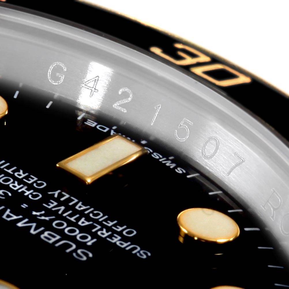 This close-up image of a Rolex Submariner 116613 Men's Steel and Gold (two tone) Black Dial 116613 Men's Steel and Gold (two tone) Black Dial shows part of the dial, bezel, and serial number engraving.