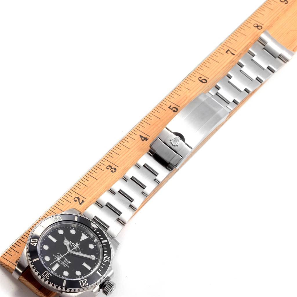 The image shows a Rolex Submariner 114060 Men
s Stainless Steel Black Dial 114060 Men
s Stainless Steel Black Dial watch laid flat with its bracelet extended alongside a wooden ruler for size reference.