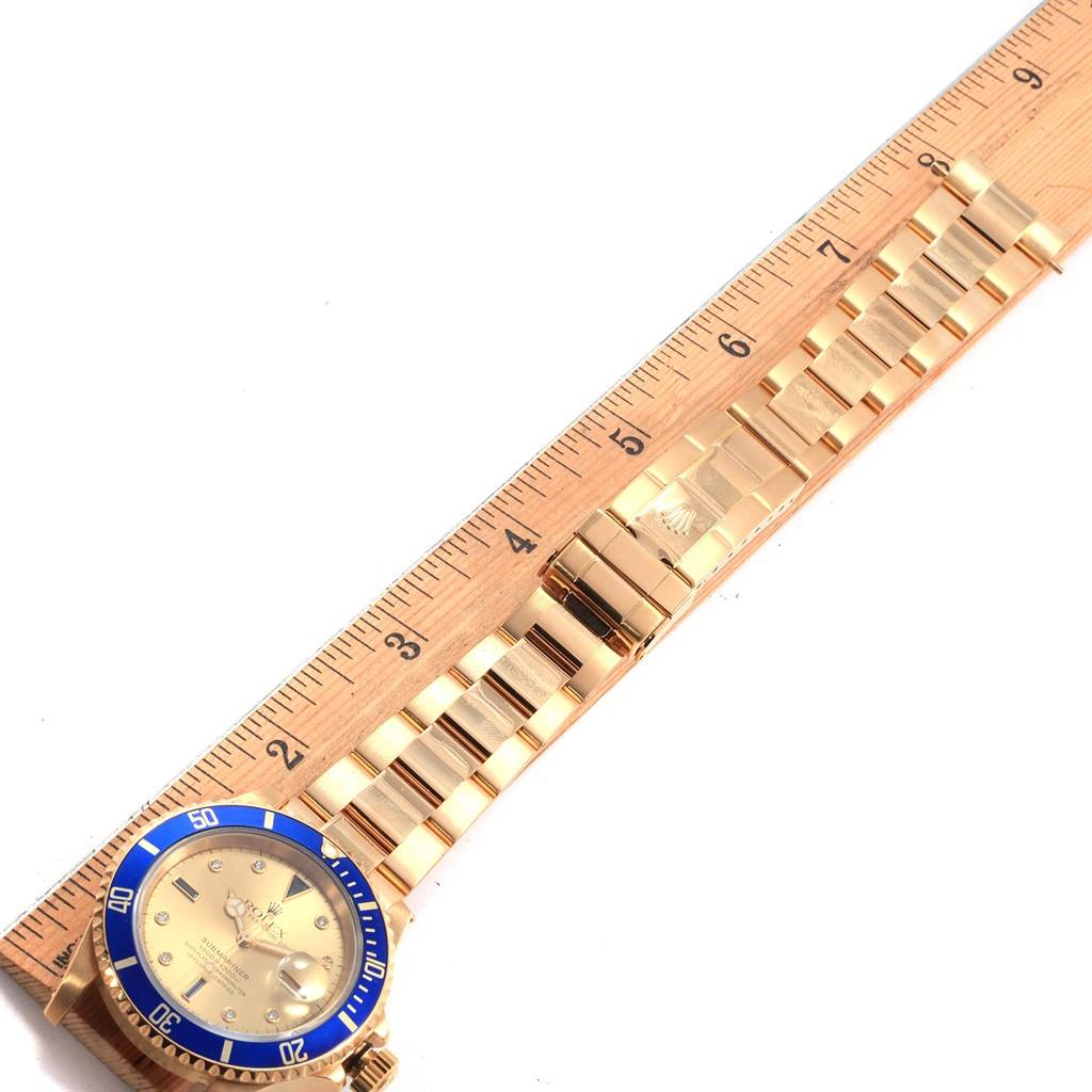 The image shows the Rolex Submariner 16618 Men's Yellow Gold Champagne Dial 16618 Men's Yellow Gold Champagne Dial watch laid flat with the case and bracelet displayed next to a ruler.