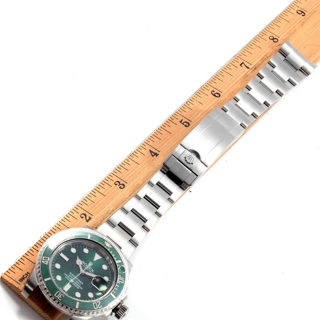This image shows a top-down view of a Rolex Submariner 116610LV Men's Stainless Steel Green Dial 116610LV Men's Stainless Steel Green Dial watch, displaying the face, bezel, and bracelet laid next to a ruler.