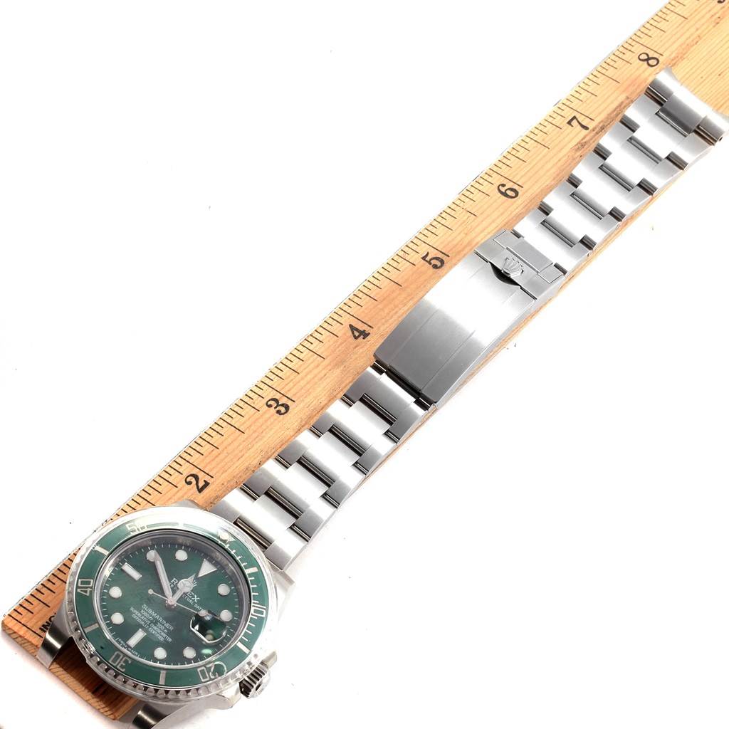 The Rolex Submariner 116610LV Men's Stainless Steel Green Dial 116610LV Men's Stainless Steel Green Dial watch is shown from a top-down angle, with a focus on its face and bracelet laid next to a ruler.
