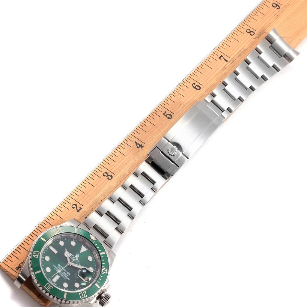 The image shows a top-down view of a Rolex Submariner 116610LV Men's Stainless Steel Green Dial 116610LV Men's Stainless Steel Green Dial watch with a green bezel, linked bracelet, and a ruler for scale.